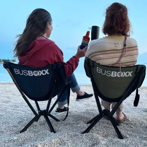 Das Bild zeigt zwei Frauen, die in einem grünen und einem blauen Campingstuhl am Strand sitzen